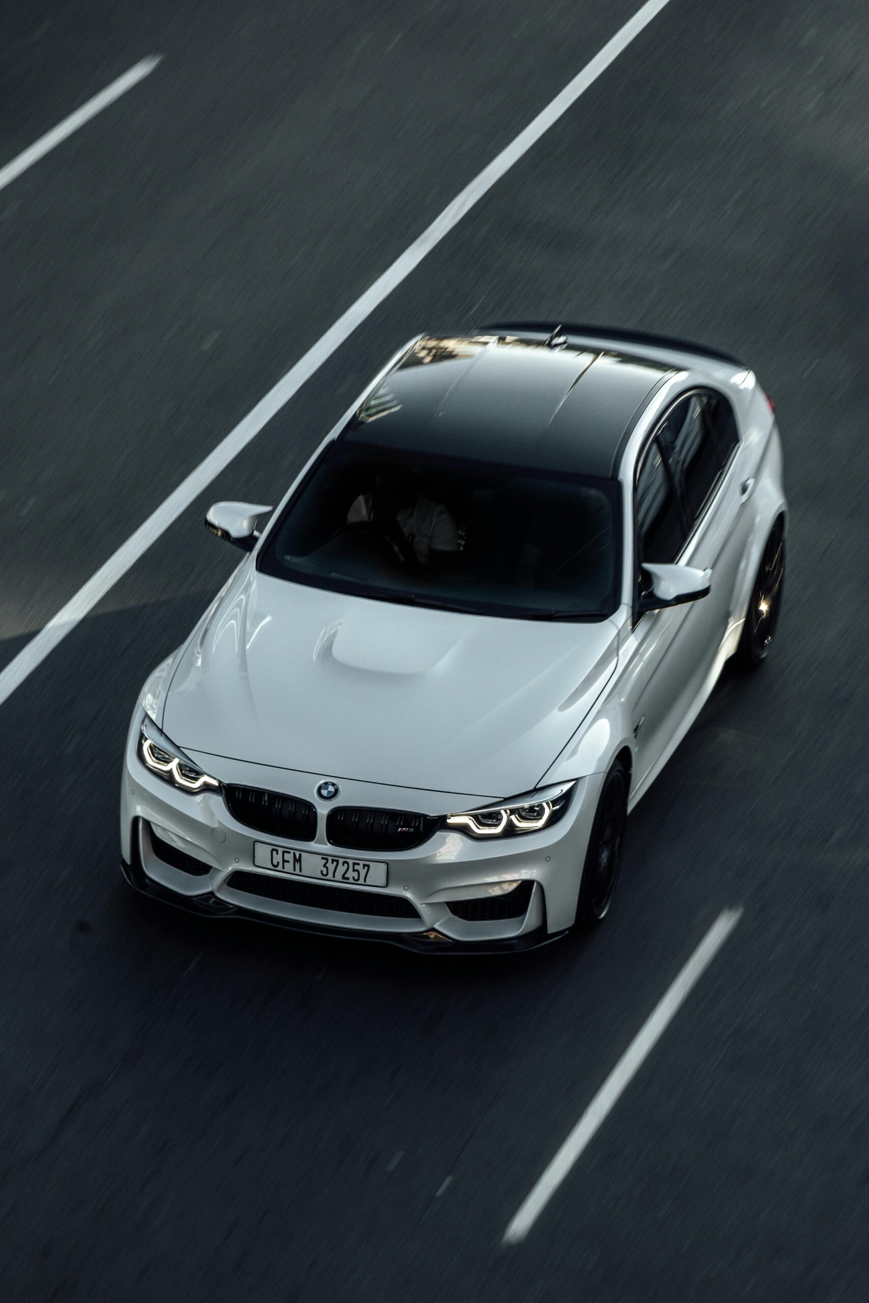 Top-down view of a luxury white car on a clear road in Cape Town.